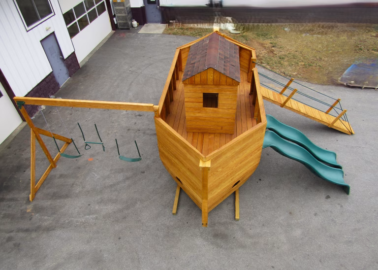 Large wooden ark-themed playset with slides, swings and gang plank.